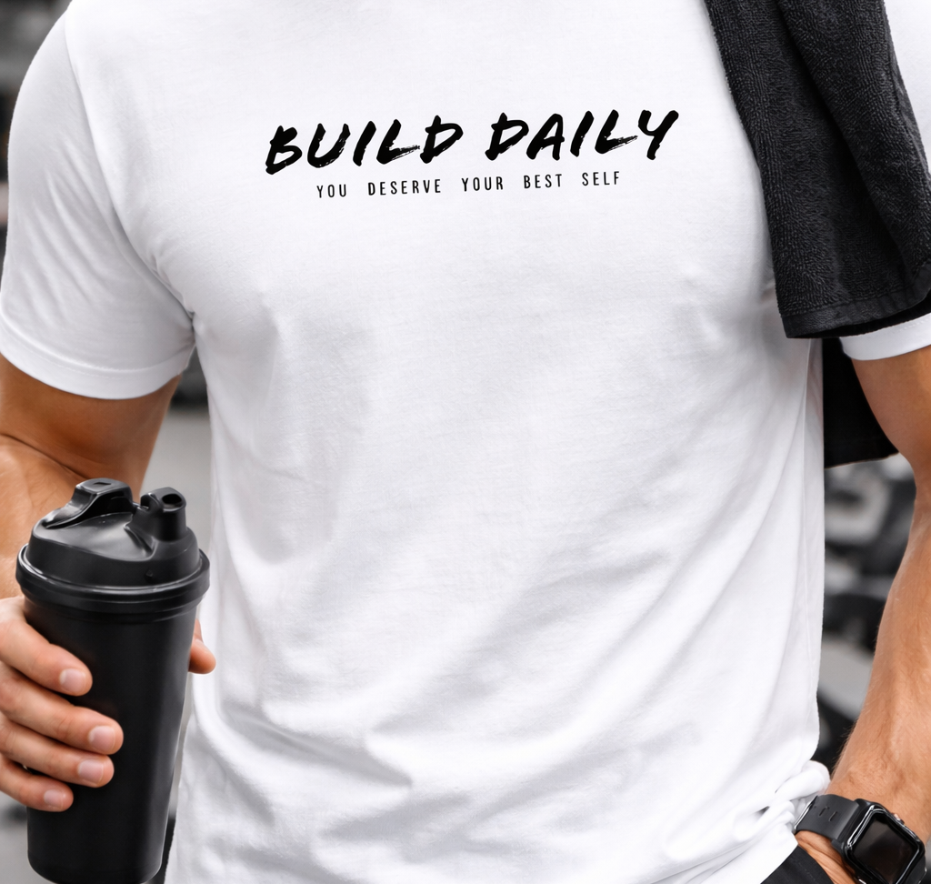 Person wearing a white t-shirt with 'Build Daily' text, holding a black shaker bottle.